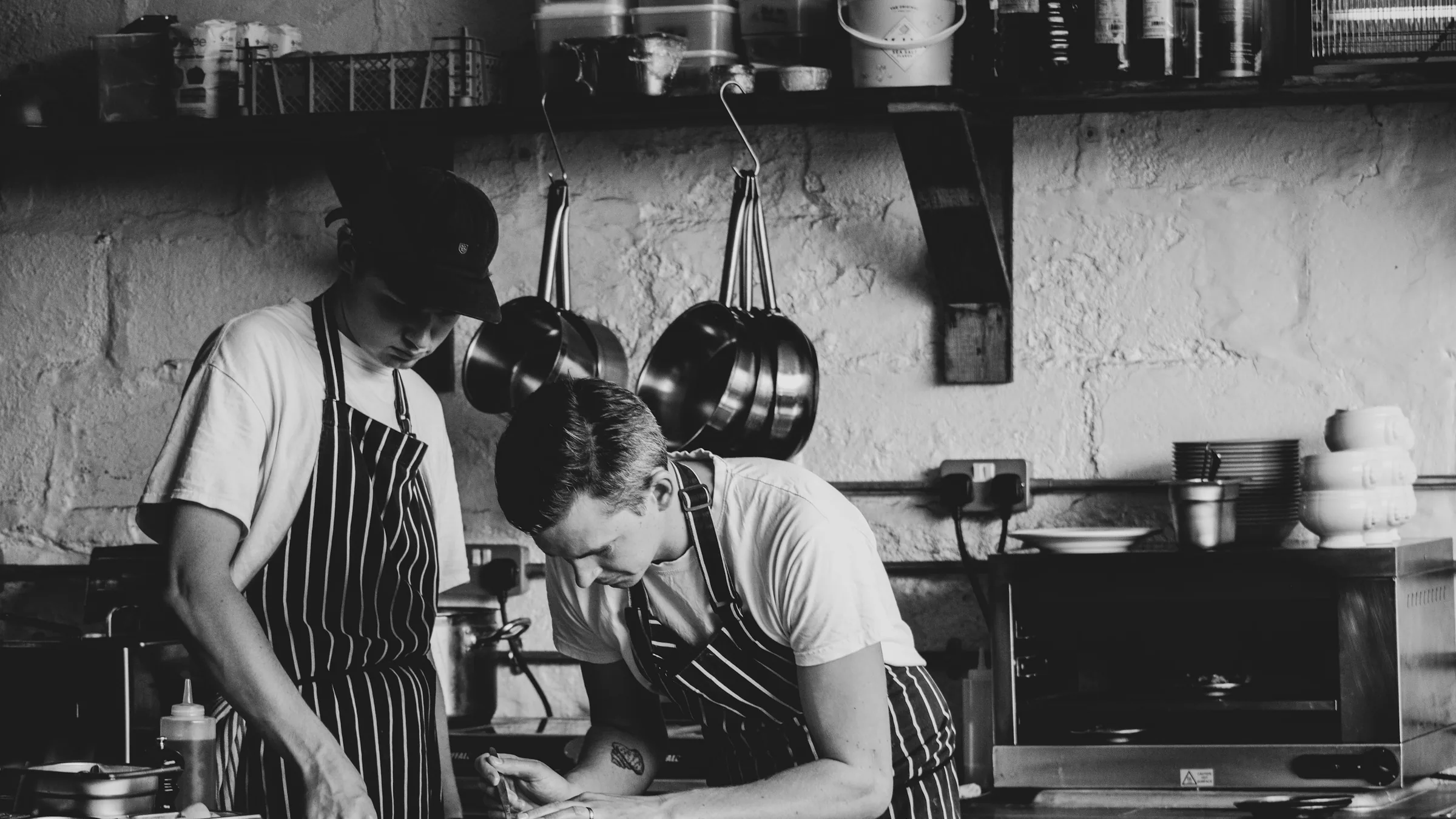 Two cooks working side by side in a kitchen, in black and white