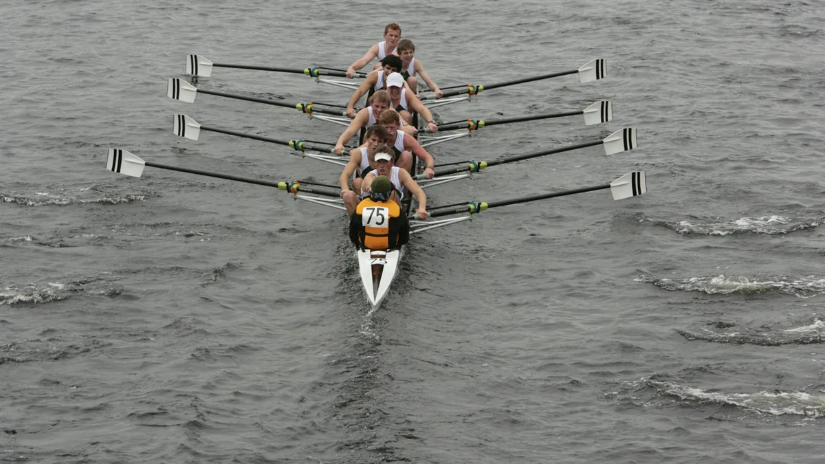 A rowing eight seen head on, the oars entering the water together