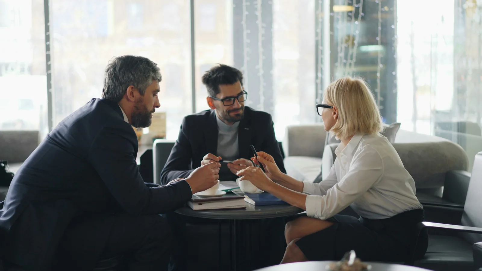 Three people at a low table in the middle of a tense conversation