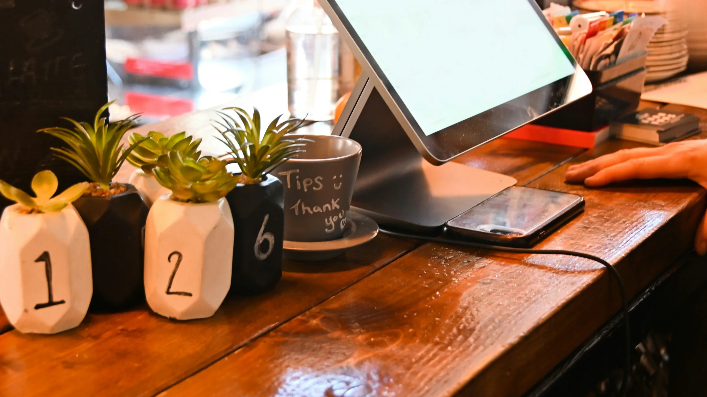 A touchscreen till on the wooden counter of a small shop