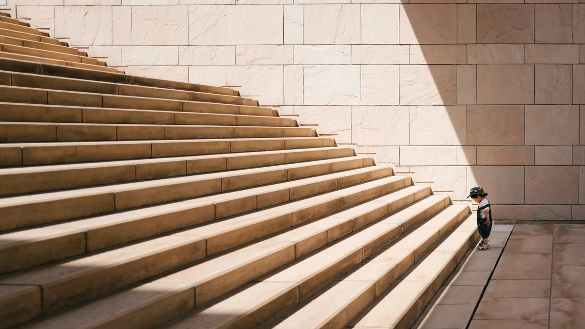 A wide stone staircase with a single figure starting the climb