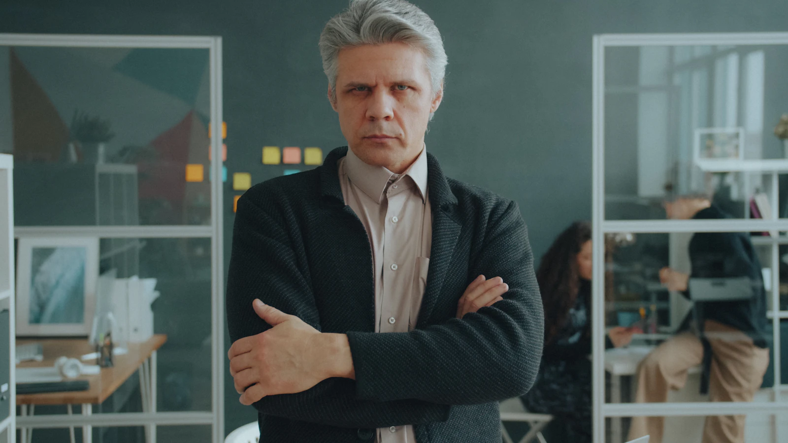 A man with grey hair and arms crossed in a modern office workspace