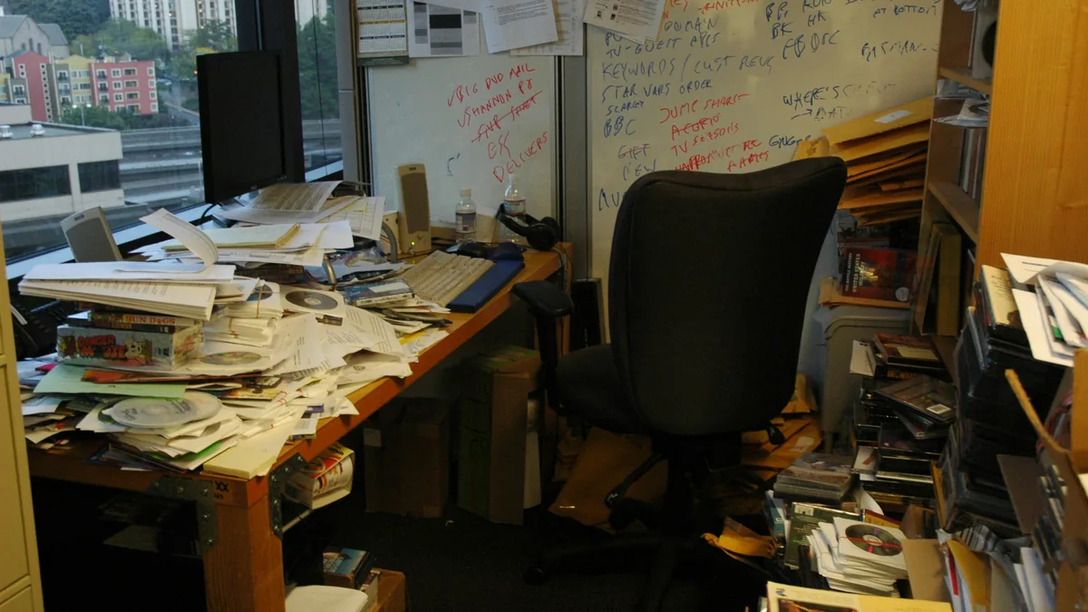 A desk buried under papers and notes in an overcrowded office