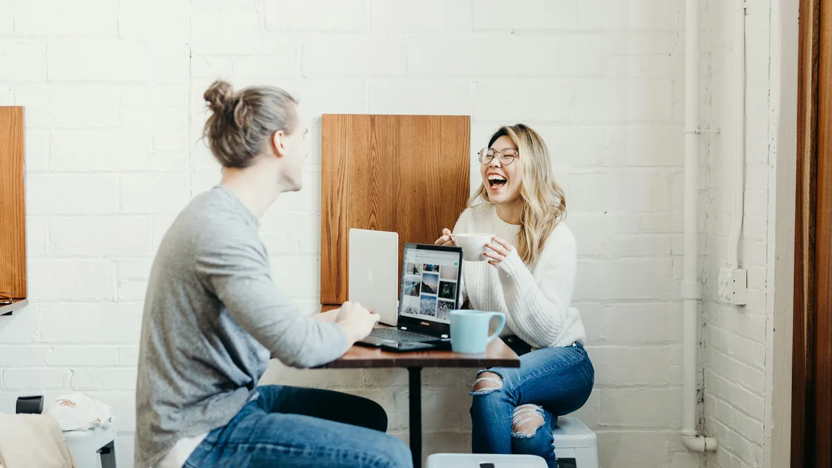 Two colleagues talking something through over a laptop at a desk