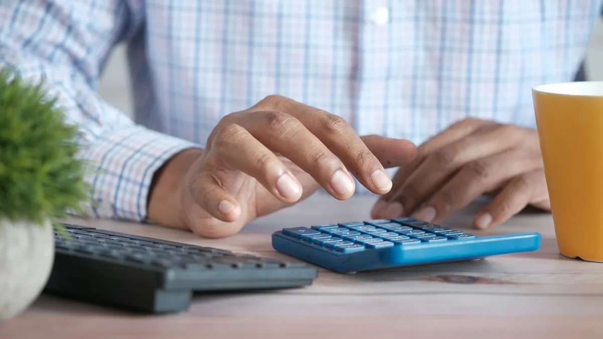 Someone entering a figure on a calculator next to their keyboard
